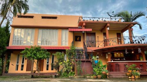 SukSanti CoLiving and Vacation في شيانج راي: منزل أصفر مع شرفة فوقه
