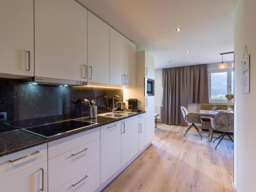 a kitchen with white cabinets and a dining room at Aparthotel Bergland in Söll