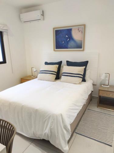1 dormitorio con 1 cama blanca grande con almohadas azules en Appartement neuf à Trou aux Biches, en Trou aux Biches