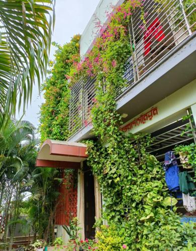 a building with lots of plants on the side of it at Mango Tree Homestay in Hampi