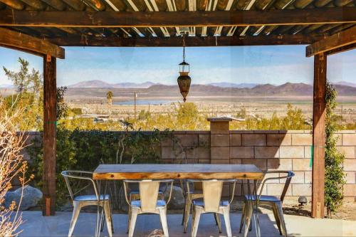 a table and chairs on a patio with a view of the desert at Breathtaking Roadrunner Heights in Joshua Tree