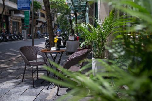 a table and chairs on a sidewalk with plants at Hanoi Diamond King Hotel & Travel in Hanoi