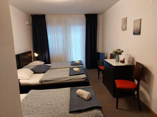a bedroom with two beds and a desk and a window at Guesthouse ob Sotočju Budič in Brežice