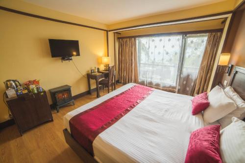 a hotel room with a large bed and a window at Denzong Regency- Luxury Mountain Retreat Spa & Casino in Gangtok