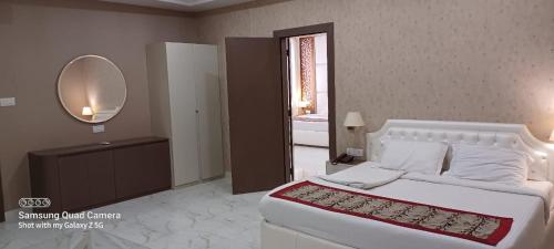 a bedroom with a large white bed and a mirror at YMCA SEACOM INN in Kolkata