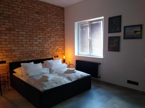 a bedroom with a bed with a brick wall at Apartament LOFT in Ostróda