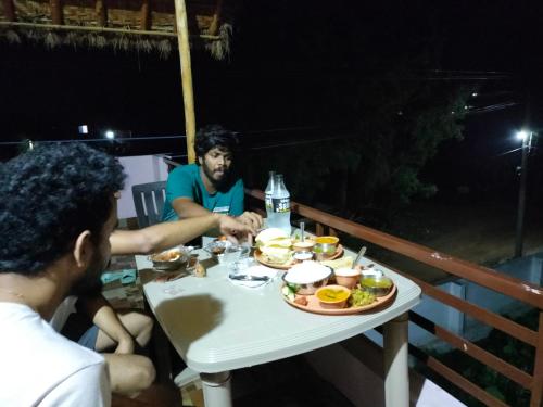two men sitting at a table with a plate of food at Prajwal home stay in Hampi