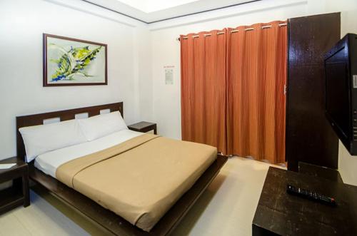 a bedroom with a bed and a flat screen tv at Taj Guesthouse Boracay in Boracay