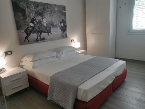 a bedroom with a large bed and a painting on the wall at Puntaalarooms in Punta Ala