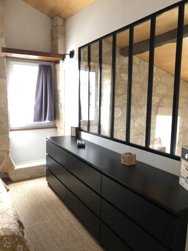 una cassettiera nera in una camera da letto con una finestra di Loft de charme centre de Montcuq a Montcuq