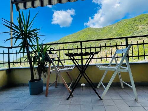 a balcony with two chairs and a table and a palm tree at Beds house, pace e tranquillità a 5 min dal mare.. in Avegno