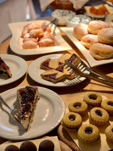 a table topped with plates of desserts and pastries at Hotel Valgranda Wellness & Spa in Val di Zoldo