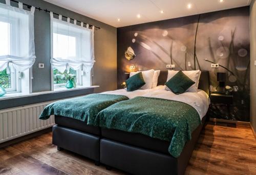 Un dormitorio con una cama grande con sábanas verdes y ventanas en B&B Poort van Westerwolde privé appartement met terras op zuiden, en Alteveer