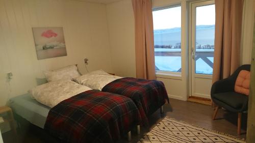 a bedroom with a bed and a chair and a window at Nesseby Guesthouse in Varangerbotn