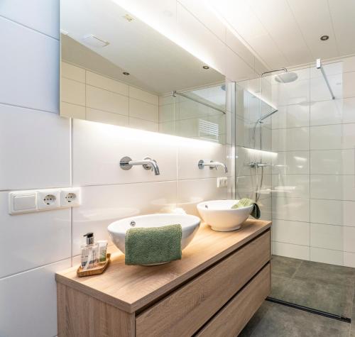 a bathroom with two sinks and a mirror at B&B Poort van Westerwolde privé appartement met terras op zuiden in Alteveer