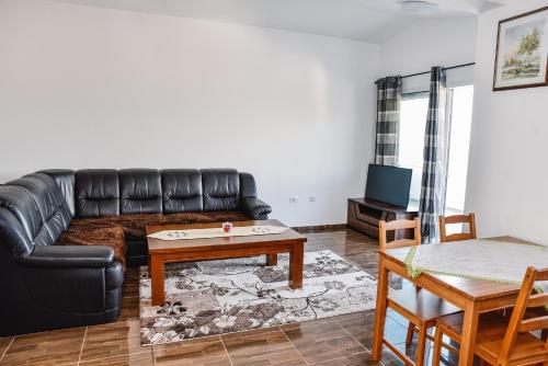 a living room with a black leather couch and a table at Seaview Apartments Bonaca in Bar