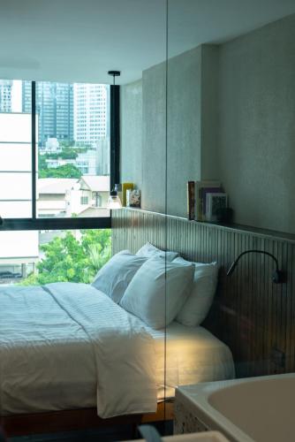 a bedroom with a bed with a window and a tub at karaarom hotel in Bangkok