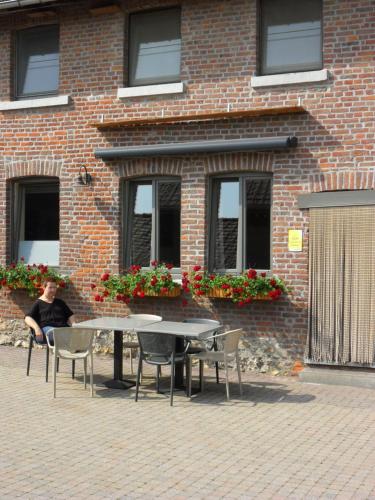 Un uomo seduto a un tavolo di fronte a un edificio di mattoni di Schophemmerhoeve a Voeren