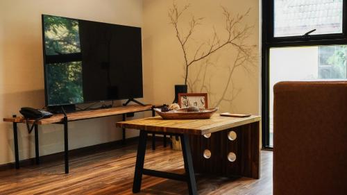 a living room with a table and a tv at karaarom hotel in Bangkok