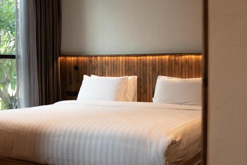 a bedroom with a large bed with white sheets and a window at karaarom hotel in Bangkok