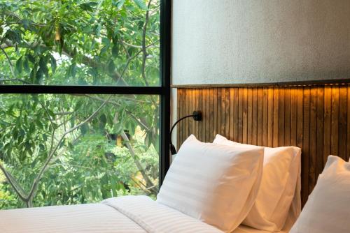 a bed with white pillows in front of a window at karaarom hotel in Bangkok