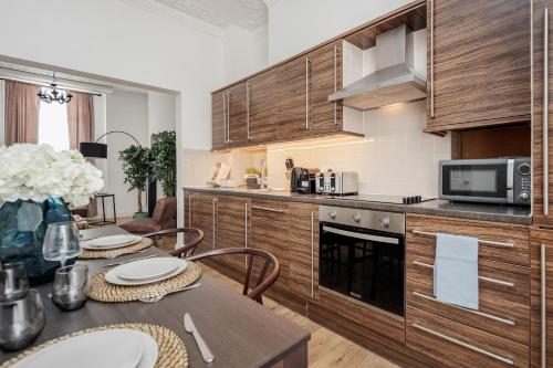 a kitchen with wooden cabinets and a table with chairs at Elegant 3Bed Apartment in Kensington Olympia in London