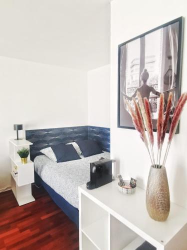 - une chambre avec un lit et une table avec un vase dans l'établissement Le 100 Brossolette, à Noisy-le-Grand