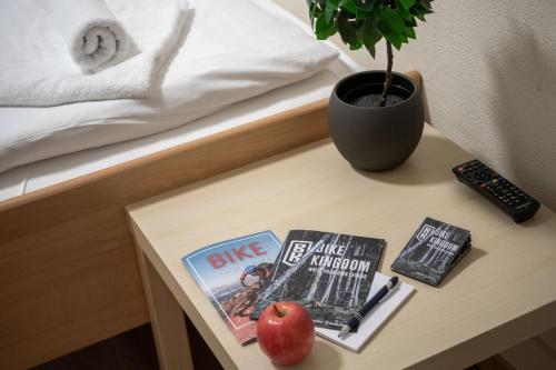 a table with two books and an apple on a bed at Grischalodge das Hotel mit Bergblick seit 1929 - schlicht, preiswert und mit einem touch Nostalgie in Parpan