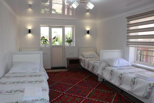 two beds in a room with two windows at Guest House Akbermet in Bokonbayevo