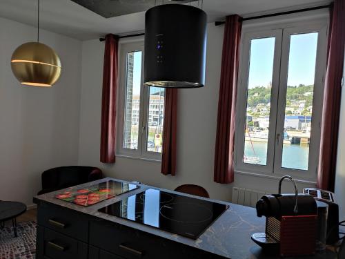 a kitchen with a counter with a sink and windows at LE REFLET DES VOILES FACE AU PORT DE FECAMP in Fécamp