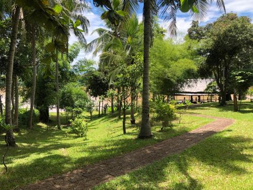 a path through a park with palm trees at On The Mekong Resort in Luang Prabang