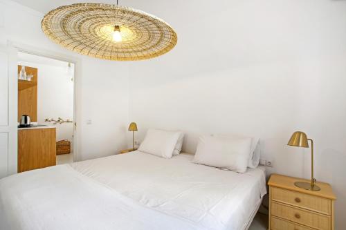 Habitación blanca con cama y lámpara de araña. en H43 Cabopino en Marbella