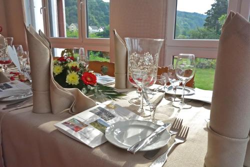 a table with glasses and plates and flowers on it at Weinhotel Landsknecht in Sankt Goar