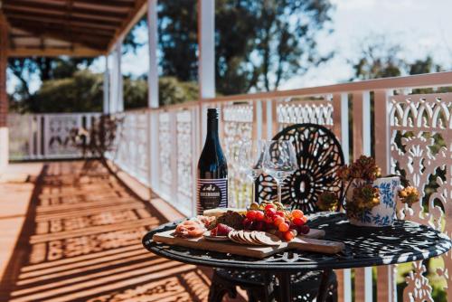 a table with a bottle of wine and a plate of food at Enfield House Mudgee in Mudgee