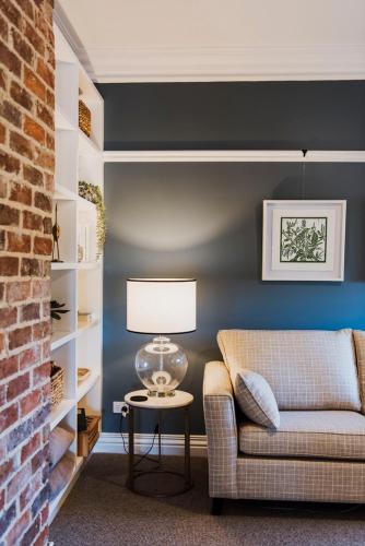 a living room with a couch and a table with a lamp at Enfield House Mudgee in Mudgee
