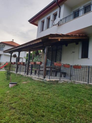 a house with a porch with chairs and a fence at Бадевски рай-къща Любов in Badewzi