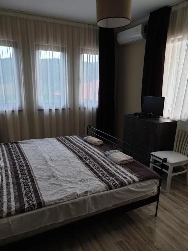 a bedroom with a bed with a television and a chair at Бадевски рай-къща Любов in Badewzi