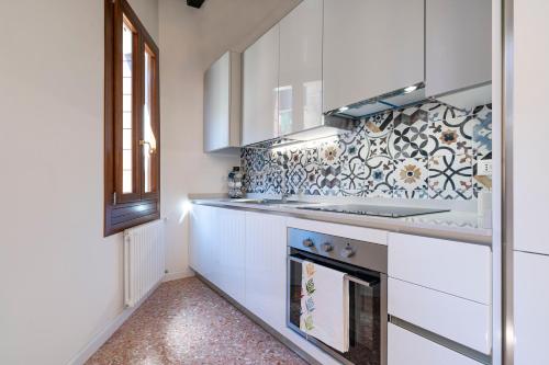a kitchen with white cabinets and a stove top oven at Querini Suite-Balcony on canal, close to San Marco in Venice