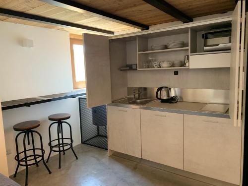 uma cozinha com armários brancos e bancos de bar em Studio with city view balcony and wifi at Cagliari 3 km away from the beach B em Cagliari