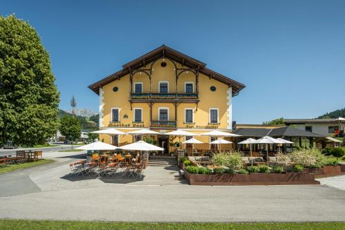 a large yellow building with tables and umbrellas at Gasthof Post St. Martin am Tgb. in Sankt Martin am Tennengebirge