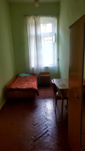 a bedroom with a bed and a window and a table at Firuza Hostel in Borjomi