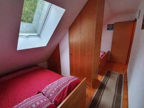 ein kleines Schlafzimmer im Dachgeschoss mit einem Bett und einem Fenster in der Unterkunft Chalet Anita Rogla in Zreče