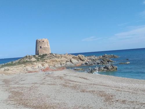 einen Leuchtturm auf einer felsigen Insel im Ozean in der Unterkunft Il Faro d'Ogliastra in Bari Sardo