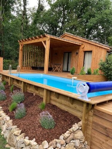 une maison avec une piscine bleue sur une terrasse en bois dans l'établissement Lodge La Courrège, à Larché
