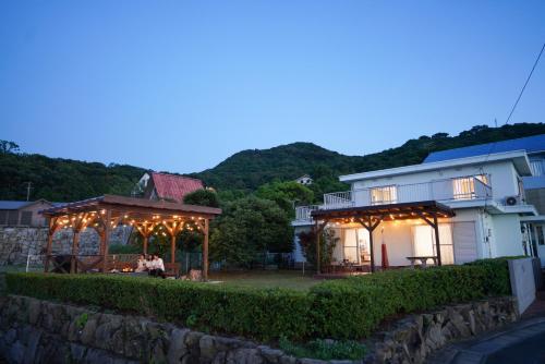 una pareja sentada bajo un cenador frente a una casa en Seaside Villa KAMANO, en Aji