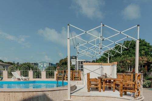 eine Terrasse mit einem Tisch und Stühlen neben einem Pool in der Unterkunft Guest House Sofia in Kobuleti