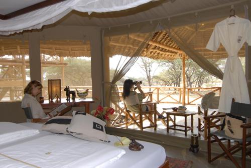 two women sitting in chairs in a room with beds at Severin Safari Camp in Tsavo West National Park