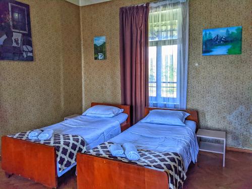 two twin beds in a room with a window at Veli Guest House • საოჯახო სასტუმრო ველი in Zemo Alvani