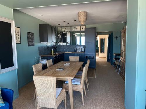 a kitchen and dining room with a wooden table and chairs at Aux Bains des Mots in Saint-Aubin-sur-Mer