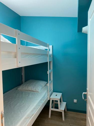 une chambre avec deux lits superposés et un mur bleu dans l'établissement Aux Bains des Mots, à Saint-Aubin-sur-Mer